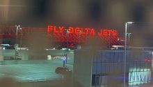Image with the red glowing Fly Delta Jets sign at the Atlanta airport shown through polka dot window tints.
