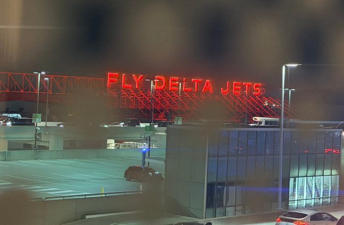 Image with the red glowing Fly Delta Jets sign at the Atlanta airport shown through polka dot window tints.